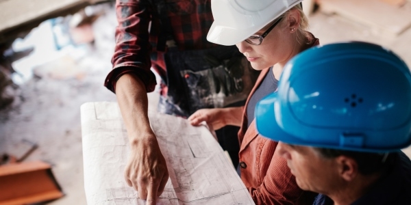 Das Bild zeigt drei Menschen bei der Planung auf einer Baustelle.