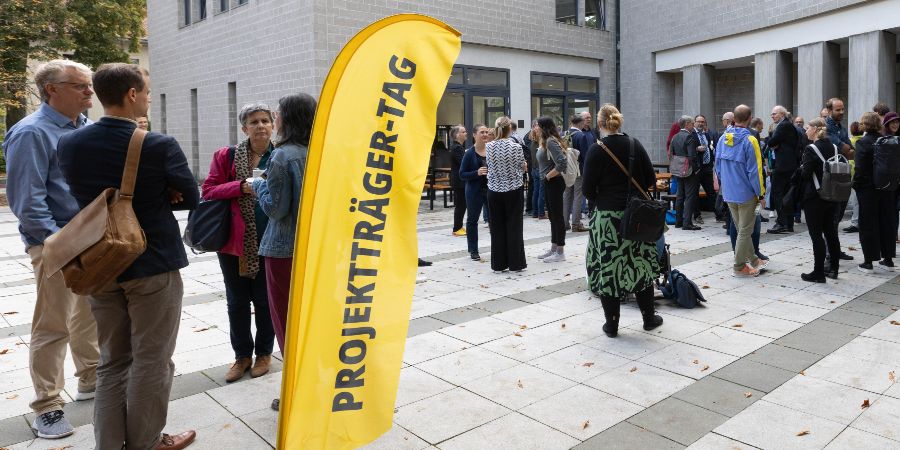 Das Bild zeigt Personen vor dem Eingang eines Gebäudes. 