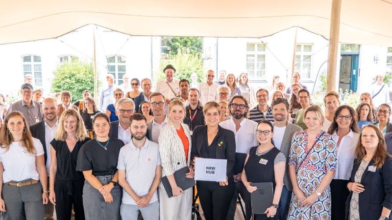 Das Bild zeigt die Gruppe aller Zuwendungsempfänger:innen. In der Mitte steht Mona Neubaur.