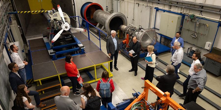 Das Bild zeigt viele Menschen, die auf einen Propeller schauen.