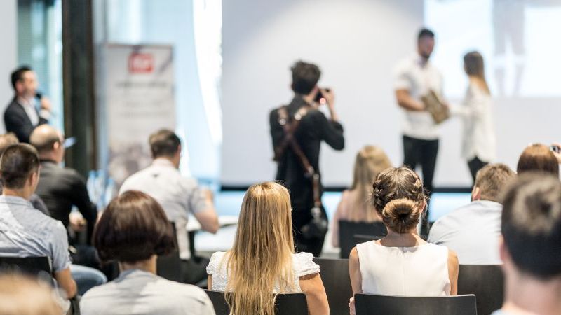Das Bild zeigt einen Mann und eine Frau, die vor einen Publikum einen Preis überreicht bekommen.