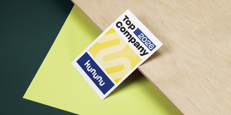 Das Bild zeigt Menschen in einem Veranstaltungsraum, die an Tischen sitzen und auf eine Präsentation auf einer Leinwand schauen.