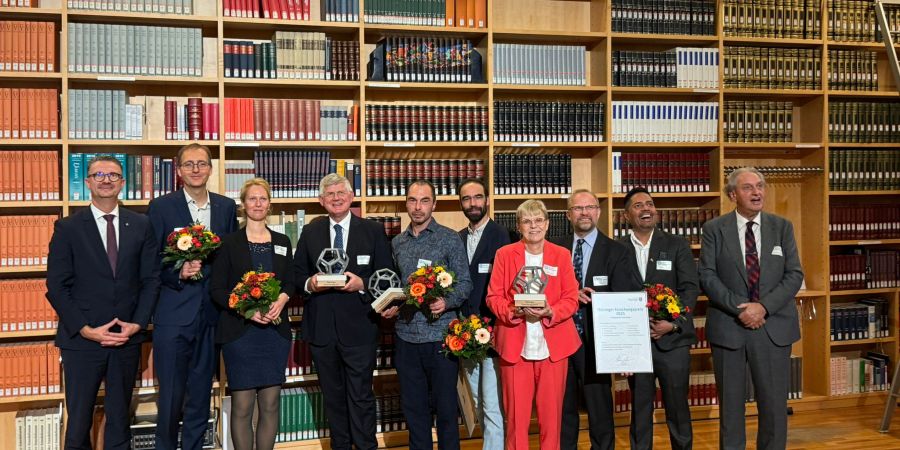 Das Bild zeigt  Menschen vor einer großen Bücherwand.