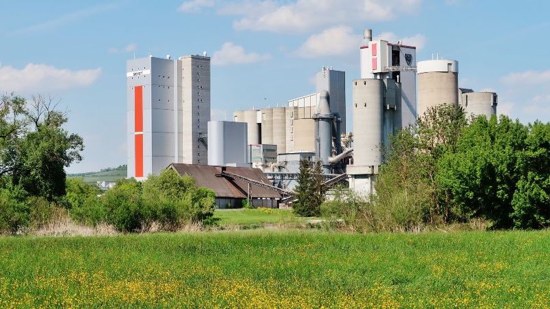 Das Bild zeigt eine Industrieanlage vor einer grünen Landschaft.