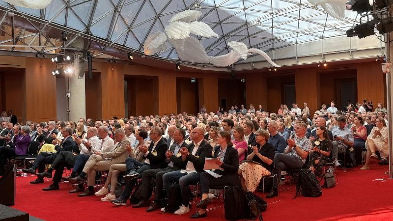 Das Bild zeigt die Teilnehmenden des PT-Forums im großen Plenum sitzend, die gespannt einem Votrag zuhören.