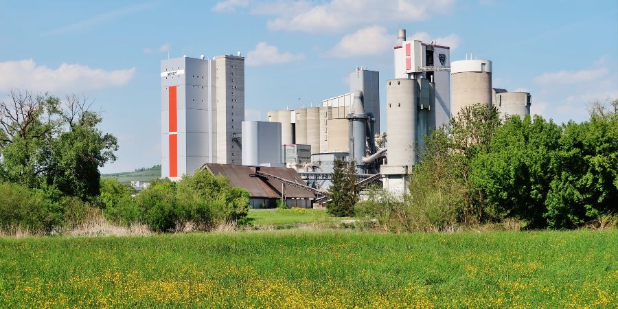 Das Bild zeigt eine Industrieanlage vor einer grünen Landschaft.