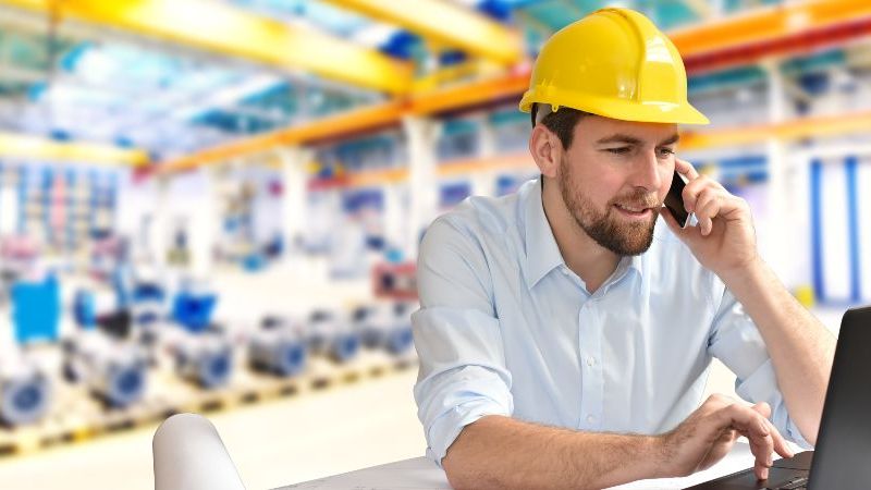 © industrieblick – stock.adobe.com Das Bild zeigt einen Ingenieur telefonierend am Arbeitsplatz in einer Fabrikhalle
