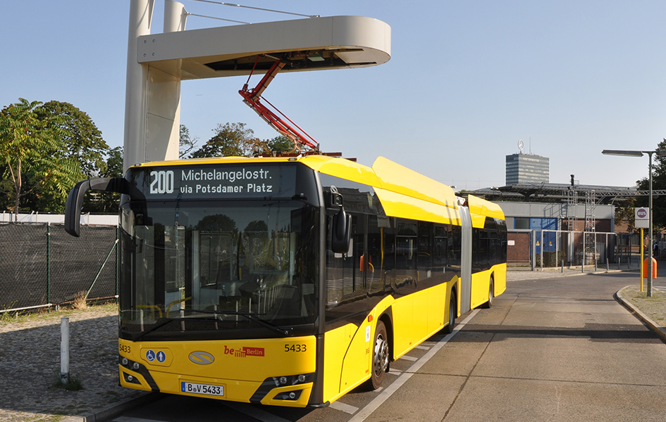 Das Foto zeigt einen Pantografen, der die Batterie eines Berliner E-Metro-Gelenkbusses über das Dach auflädt.