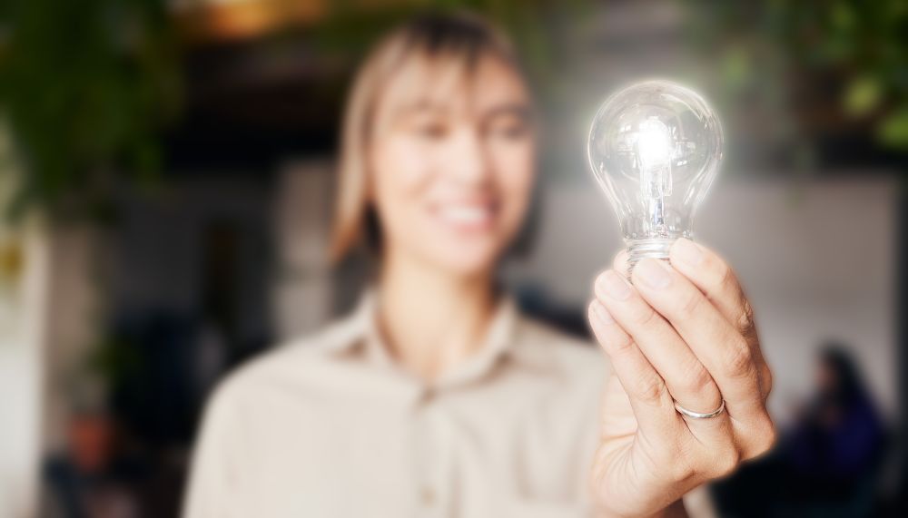 A woman holds a light bulb in the air.