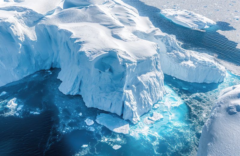 Auf dem Bild ist eine Eislandschaft am Meer zu sehen. Im Wasser treiben Eisschollen.