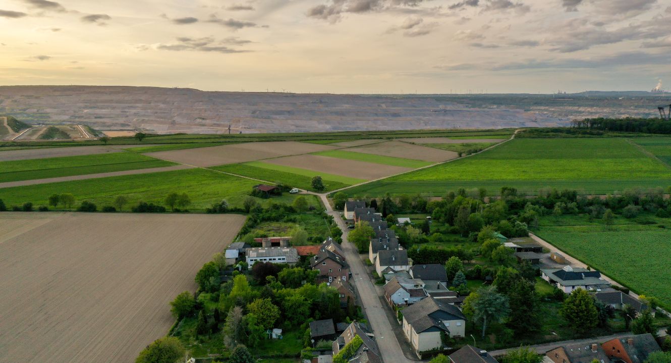 Auf dem Bild ist ein Dorf vor einem Tagebau zu sehen.