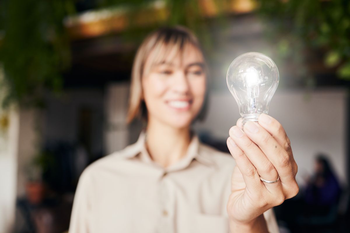 A woman holds a light bulb in the air.