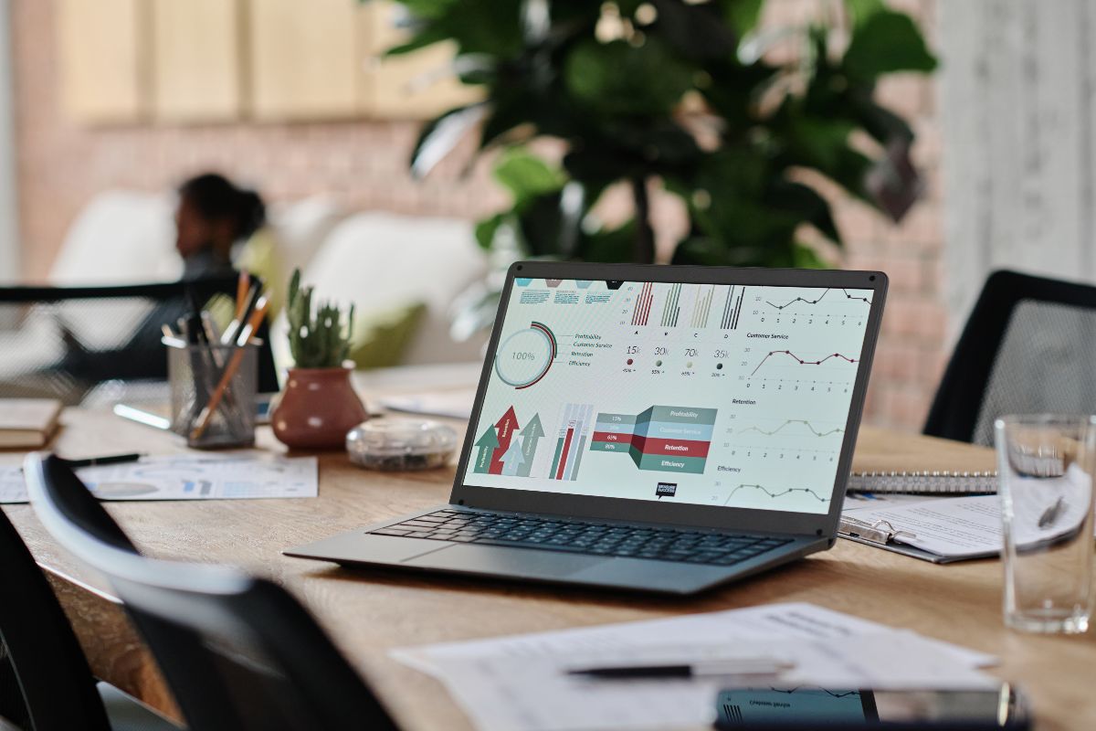 A laptop is sitting on a table. Several charts and analyses are displayed on the laptop.