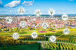 Blick über einen Weinberg hin zu einer Ortschaft, illustriert mit Symbolen der Zukunftstechnologie