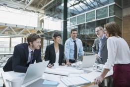 The image shows five people in a meeting.