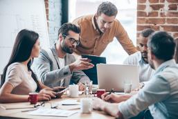 The image shows a group of young people working together at a table.